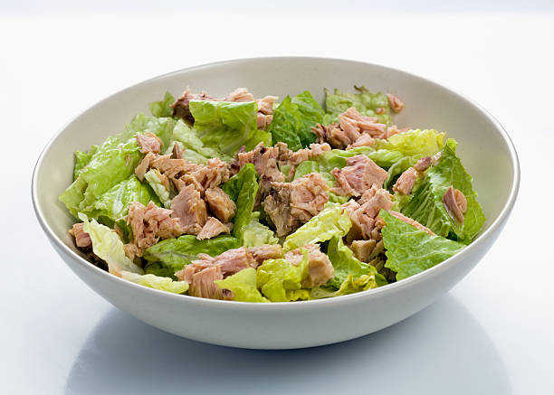 canned tuna in ceramic bowl on wooden cutting board top view. Seafood