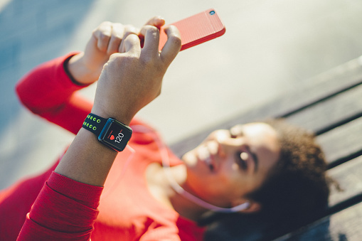 Mixed race woman lying on bench and listening to music