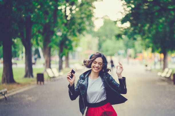 счастливая девушка, наслаждающаяся хорошей музыкой в парке - walking girl стоковые фото и изображения