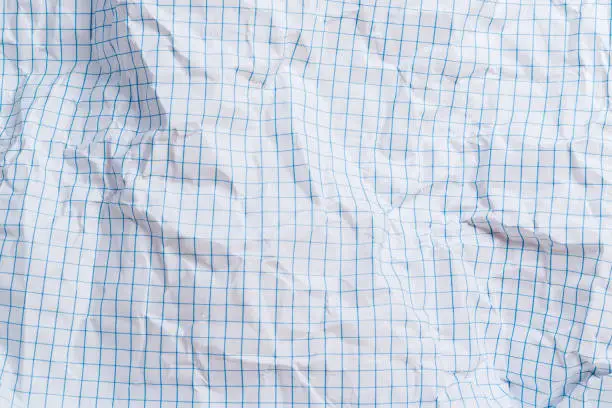 Photo of A sheet of folded and torn blue squared paper