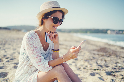 Relaxed woman on vacation online banking on smartphone