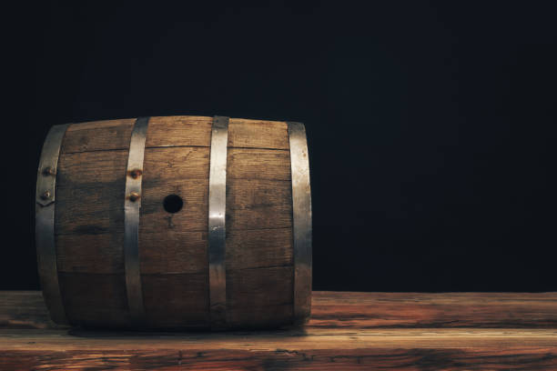 istock Wooden barrel on a old oak table. Black background behind. 1142401049