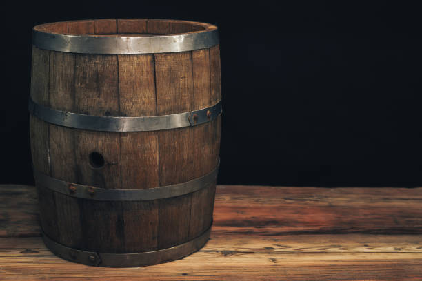 istock Wooden barrel on a old oak table. Black background behind. 1142401110