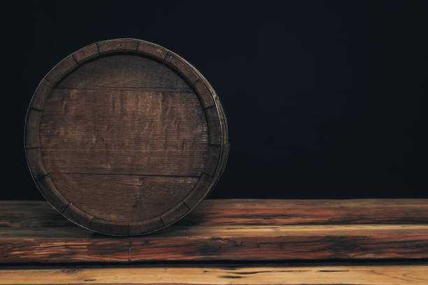 istock Wooden barrel on a old oak table. Black background behind. 1142401204