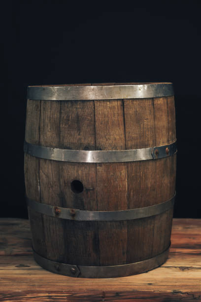 istock Wooden barrel on a old oak table. Black background behind. 1142401230
