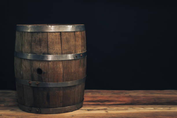 istock Wooden barrel on a old oak table. Black background behind. 1142401238