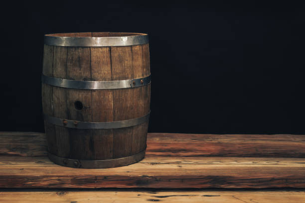 istock Wooden barrel on a old oak table. Black background behind. 1142401252