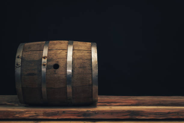 istock Wooden barrel on a old oak table. Black background behind. 1142401328