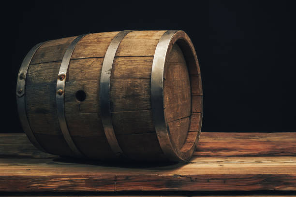 istock Wooden barrel on a old oak table. Black background behind. 1142401391