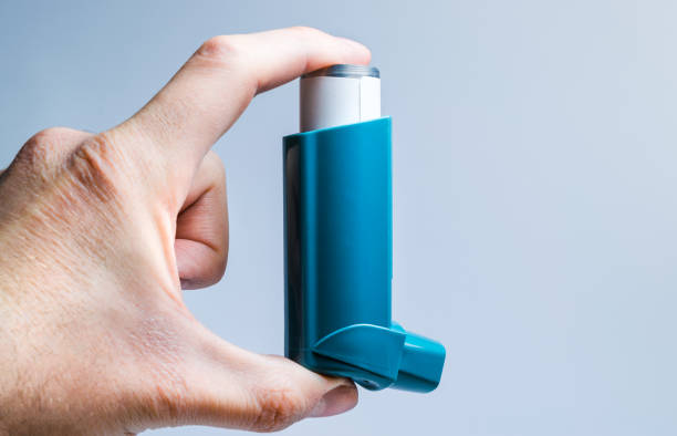 A hand holds a medical inhaler for asthma and lung diseases stock photo