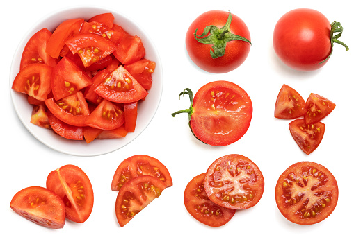 Set of fresh whole and sliced tomatoes isolated on white background. Top view.