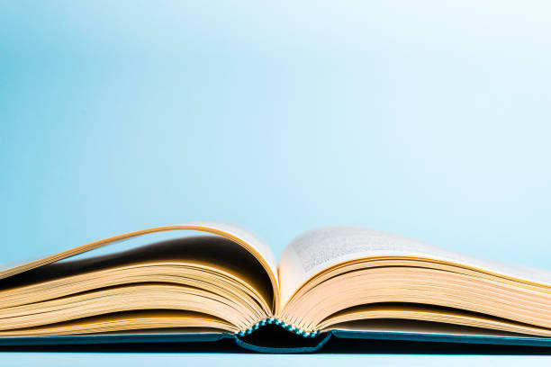 An old book with yellow pages and a hardcover half open on a blue background