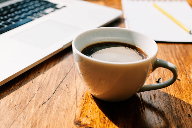 istock Black coffee, laptop on a desk in bright sunshine. 1142405192