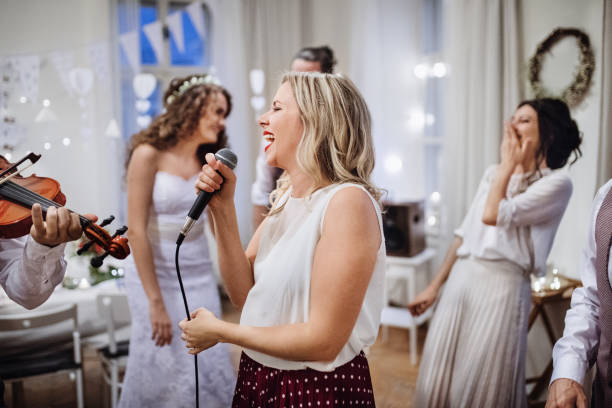 istock A young woman singing on a wedding reception, bride and guests dancing. 1142413292