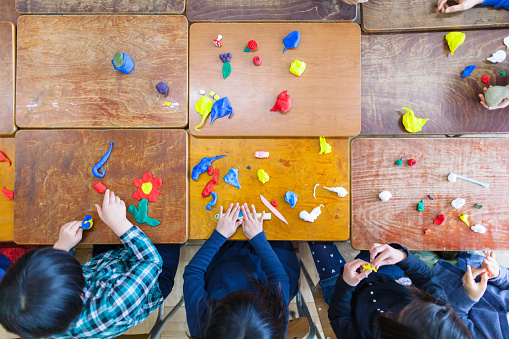 Group of children are playing with clay in classroom.