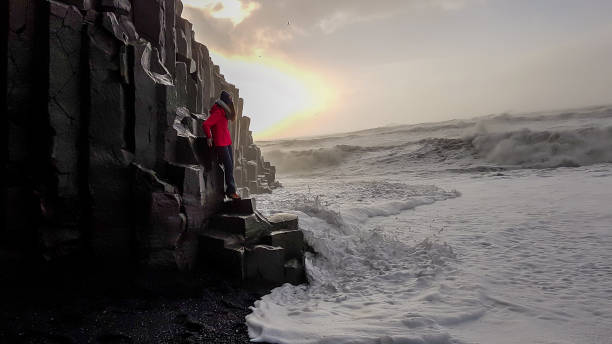 istock Iceland - Girl standing at the basalt column when the wave washes in 1142416680