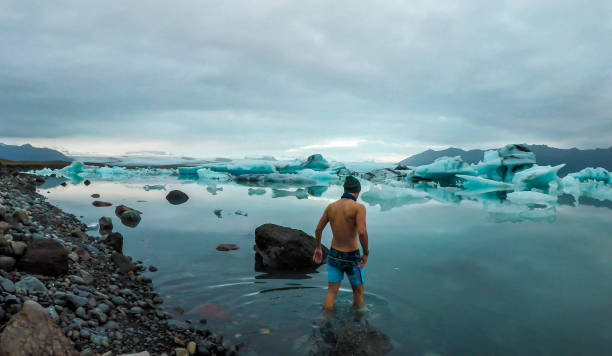 islande-homme entrant dans la lagune glaciaire - iceland nature glacier ice photos et images de collection