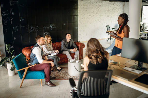 Group of young colleagues discussing new business ideas in the modern office while drinking coffee