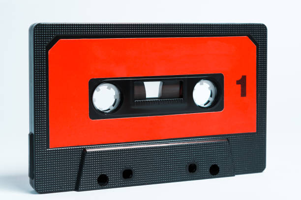 A red and black audio cassette with roll-up tape and isolated on white background stock photo