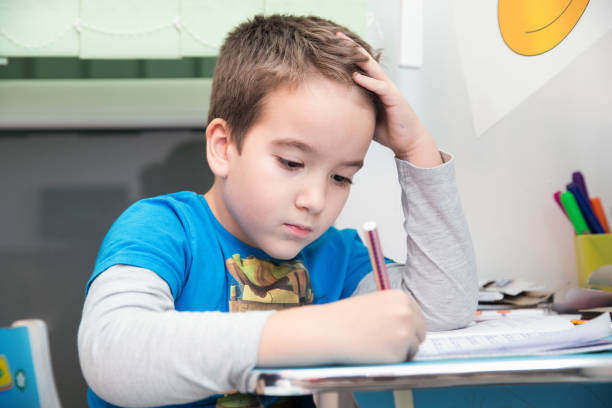 istock Schoolboy is using pen to practice writing on a notebook at his desk at home 1142424089