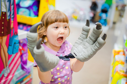 Little kid girl having fun at the children shop, choosing toys, lifestyle.