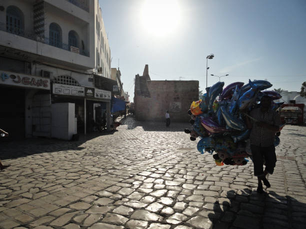 Sousse, Tunisia - July, 2014: A man with balloons is walking on a cobbled square in backlight