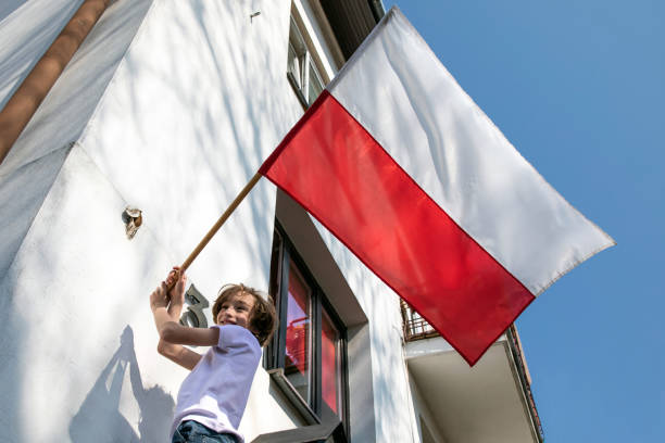 мальчик вешает флаг. национальный день польши третьего мая, день конституции - polish flag стоковые фото и изображения