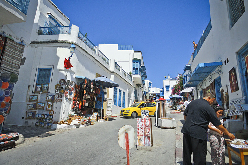 Sidi Bou Said, Tunisia - July, 2014: A street with white houses with blue trim and a market with plates