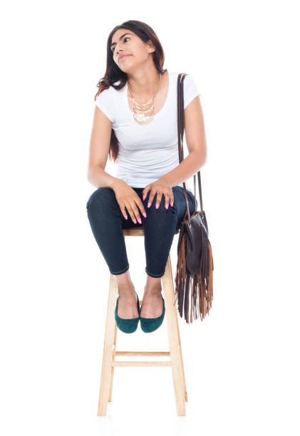 istock Beautiful latino female sitting on a stool who is bored 1142428326