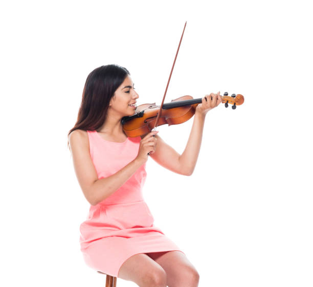 istock Attractive young latino female playing the violin while sitting on stool 1142428550