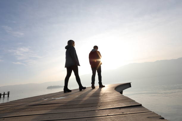 istock Two people walk along boardwalk above a lake at sunrise 1142432878