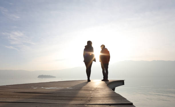 istock Two people walk along boardwalk above a lake at sunrise 1142433176