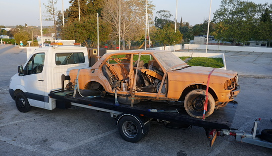 Transporting an old, broken, rusty car with a tow truck