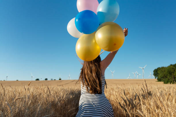 mädchen mit bunten luftballons läuft auf den weg zur windenergie-windenergiekonzept - fuel and power generation power wind power supply stock-fotos und bilder