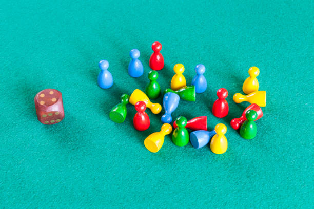 dice and many wooden board game pawns on green baize table