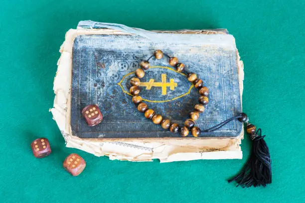 Photo of old book, worry beads and dices with six points