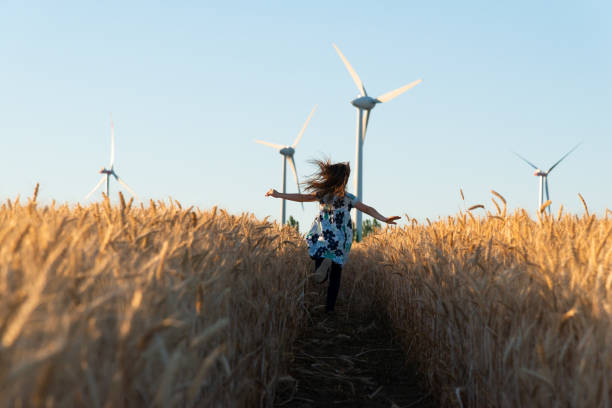 dziewczyna biegnie drogą do energii wiatrowej - wiatr turbina zdjęcia i obrazy z banku zdjęć