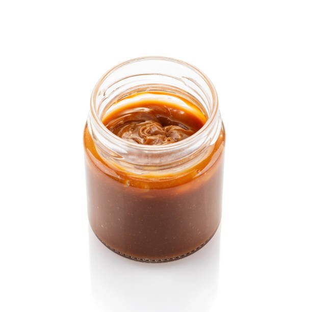 Salted caramel sauce in jar isolated on white Soft Milk Caramel in glass jar isolated on white background. Salted caramel sauce or Dulce de Leche, melted caramel sauce dulce de leche stock pictures, royalty-free photos & images