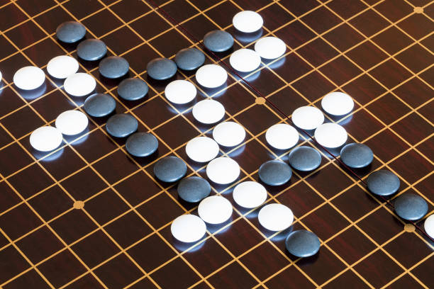 istock playing stones on wooden board in Go 1142446013