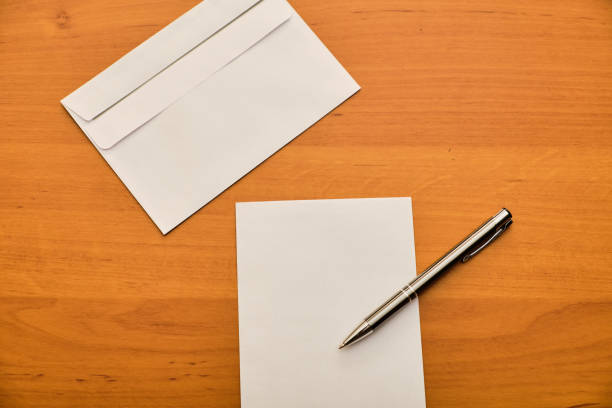 istock Paper, modern envelope and metal ballpoint on wooden table 1142450863