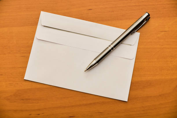istock Modern envelope and metal ballpoint on wooden table 1142450943