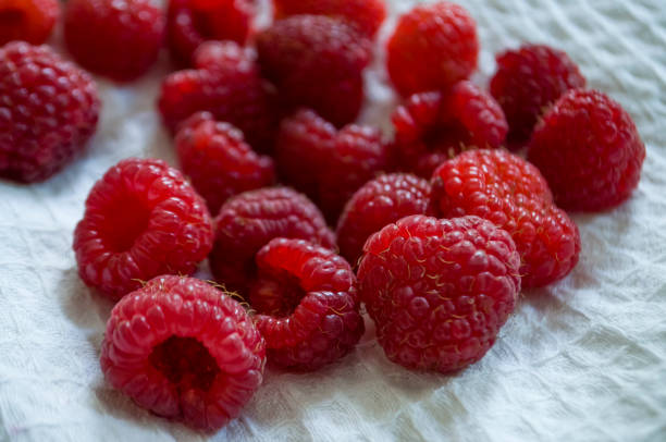 istock Big ripe raspberries are laying on the  table covered with white tablecloth 1142451277