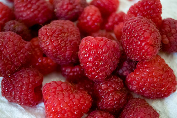 istock Big ripe raspberries are laying on the  table covered with white tablecloth 1142451298