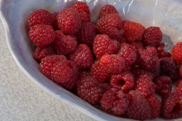 istock Big ripe raspberries are laying on the  table covered with white tablecloth 1142451411