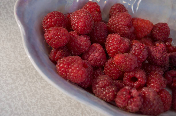 istock Big ripe raspberries are laying on the  table covered with white tablecloth 1142451458