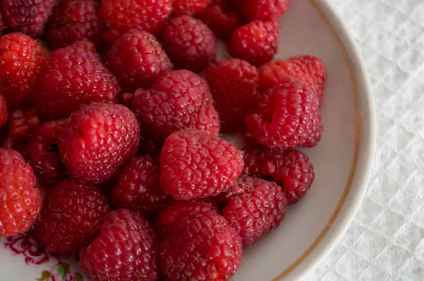 istock Big ripe raspberries are laying on the  table covered with white tablecloth 1142451985