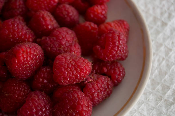 istock Big ripe raspberries are laying on the  table covered with white tablecloth 1142452521