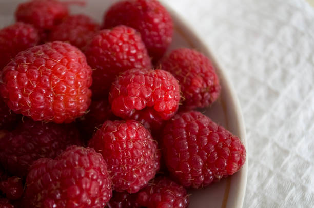 istock Big ripe raspberries are laying on the  table covered with white tablecloth 1142452545