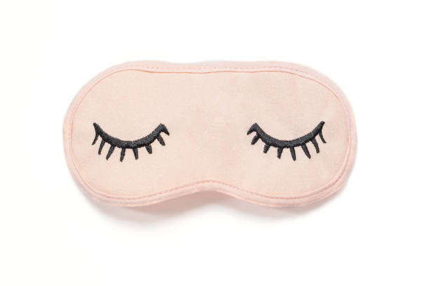 istock Pastel pink sleep mask with closed eyes embroidered on it with eyelashes on white background. Top view, flat lay. Concept of vivid dreams. Accessories for girls and young women. 1142468400