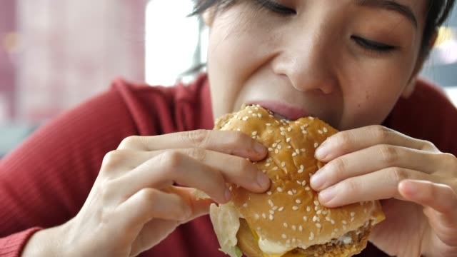 Asian Woman eating hamburger